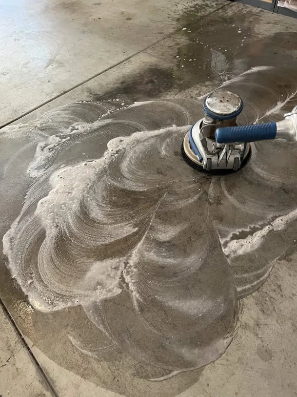 Concrete floor being polished with a planetary polishing machine creating circular swirl patterns