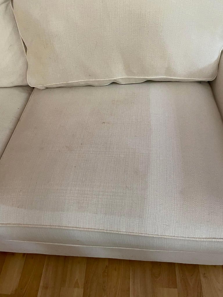 Beige upholstered armchair with cushions on hardwood floor