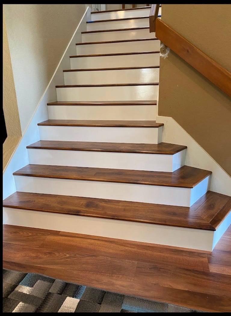 Interior staircase with wooden steps and white risers, flanked by white and wood railings, photographed from below